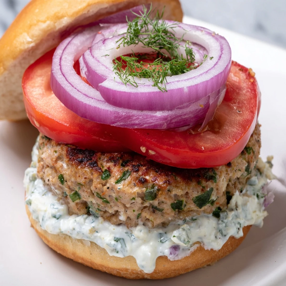 Juicy Greek chicken burgers with feta, crisp vegetables, and zesty homemade tzatziki sauce