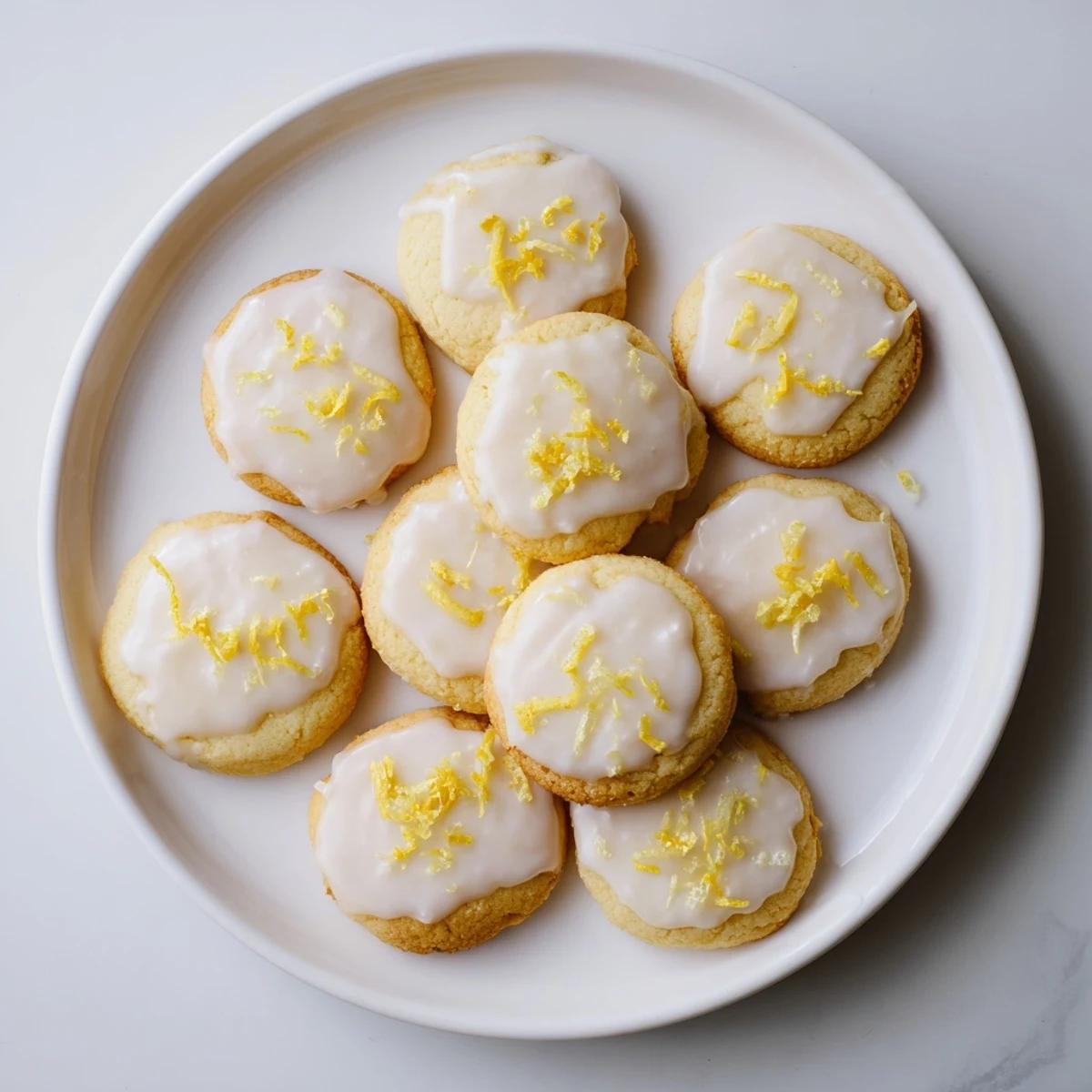 Buttery lemon cookies with glossy Limoncello frosting cooling on a wire rack with citrus garnish.