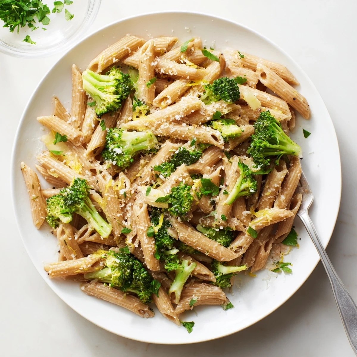 Vibrant broccoli and penne pasta dish glistening with light olive oil sauce and lemon zest garnish
