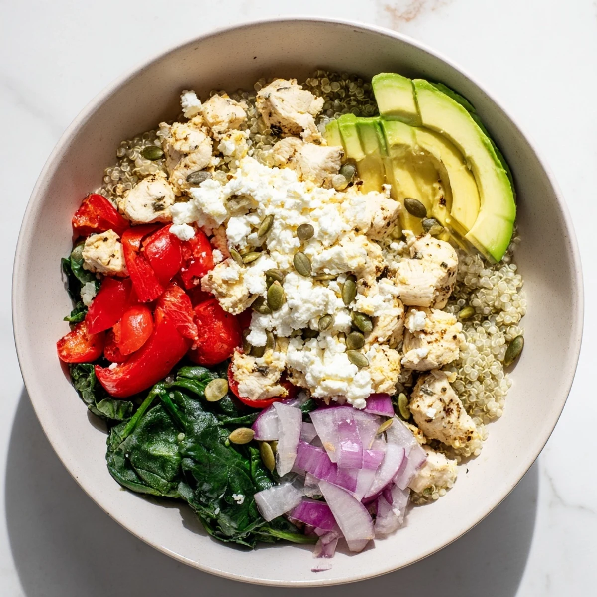 Colorful breakfast bowl featuring scrambled eggs, fresh vegetables, avocado slices, and protein-rich toppings