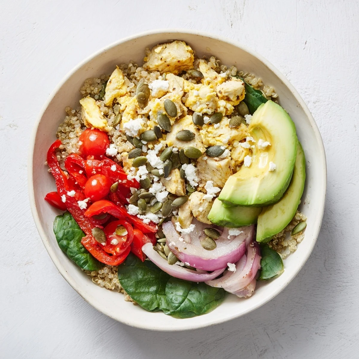 High protein breakfast bowl with fluffy eggs, spinach, tomatoes, and creamy avocado in a serving bowl
