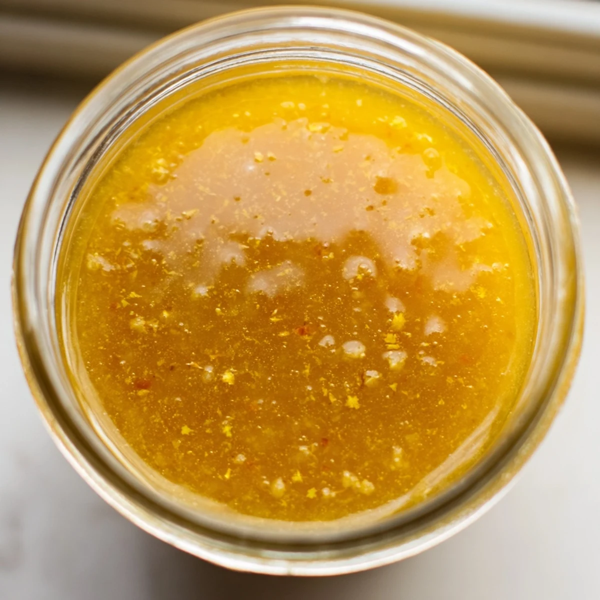 Golden citrus vinaigrette emulsified in a glass jar ready for drizzling over fresh salads