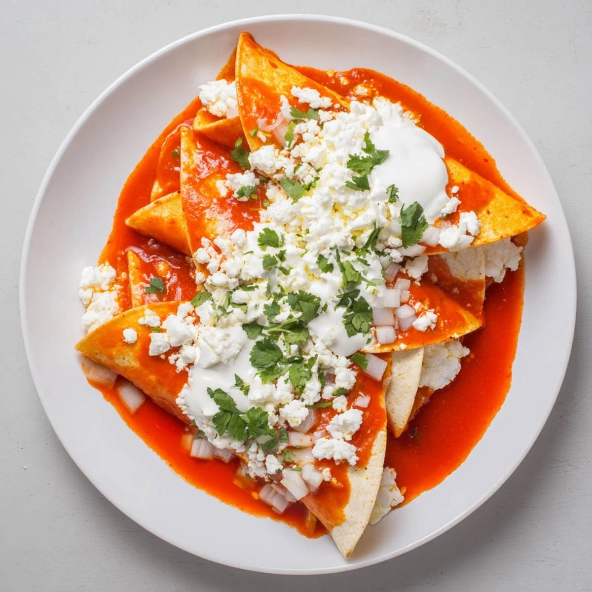 Warm entomatadas folded and smothered in vibrant tomato sauce with creamy Mexican crema drizzle