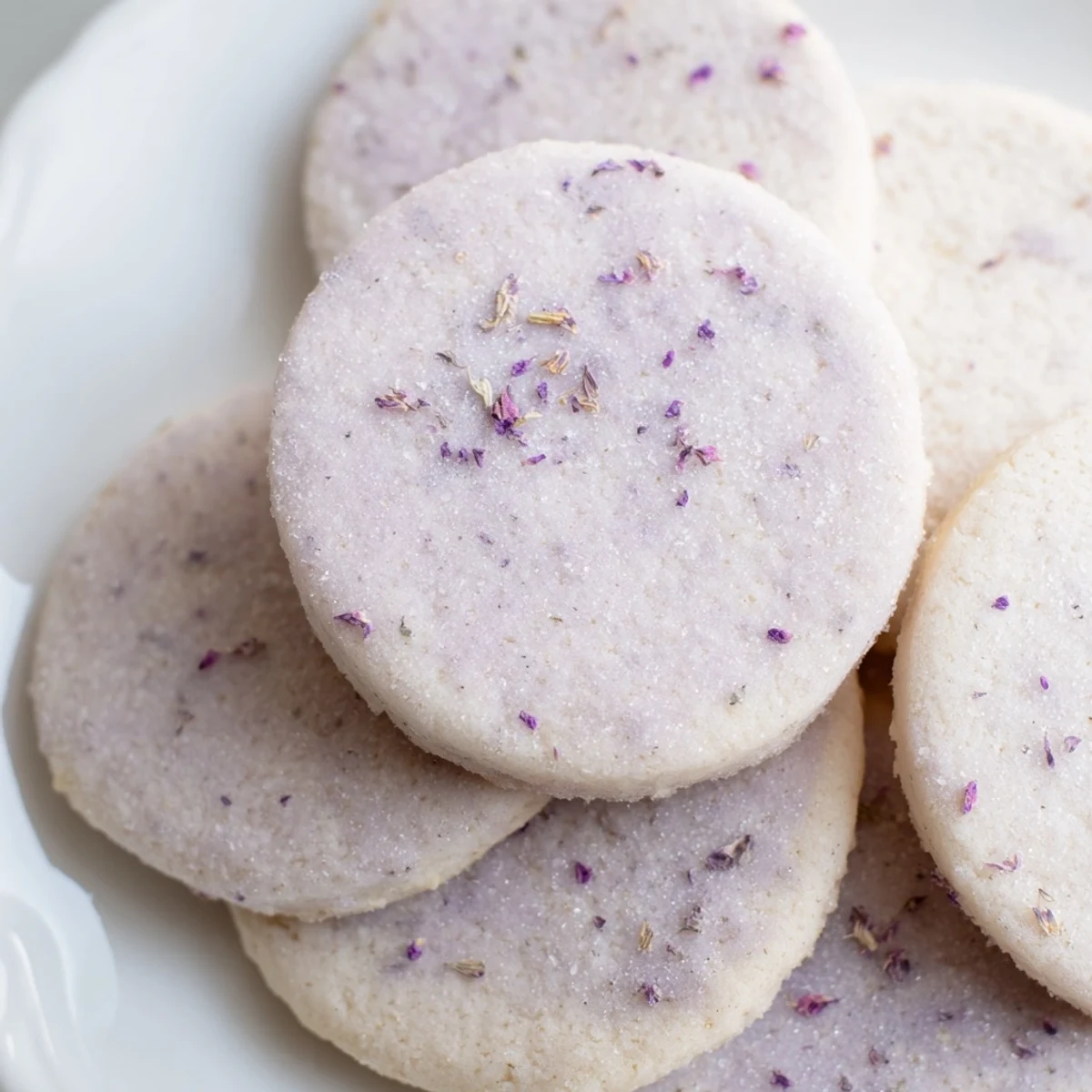 Buttery lilac sugar cookies arranged on a rustic white serving plate