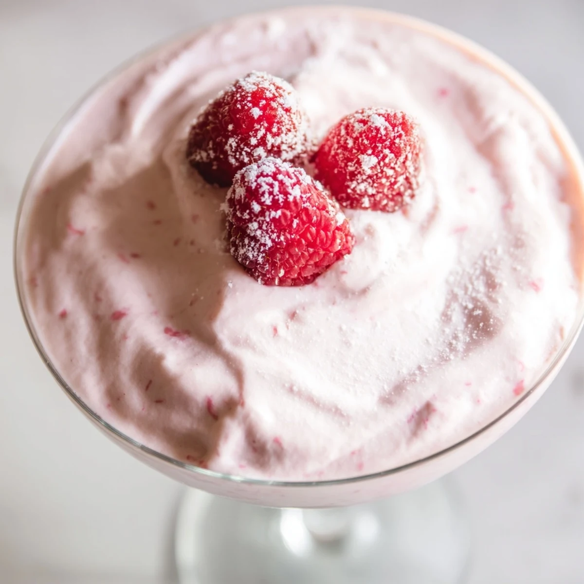 Light and airy raspberry cloud mousse garnished with bright red fresh raspberries