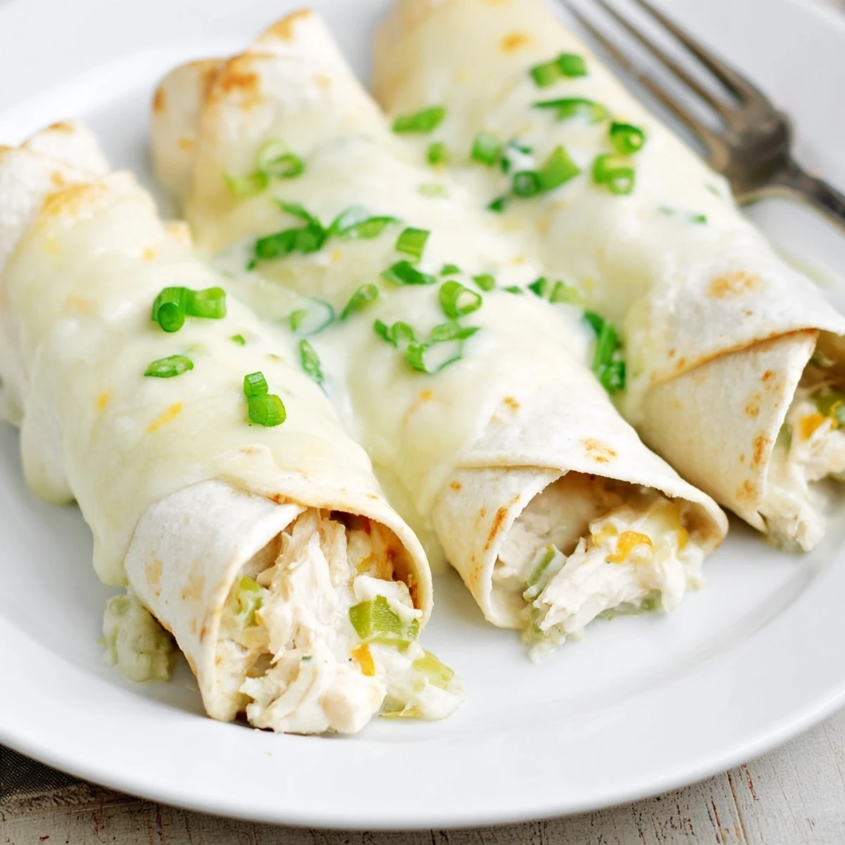 White Rotisserie Chicken Enchiladas bubbling with creamy white sauce and melted Monterey Jack