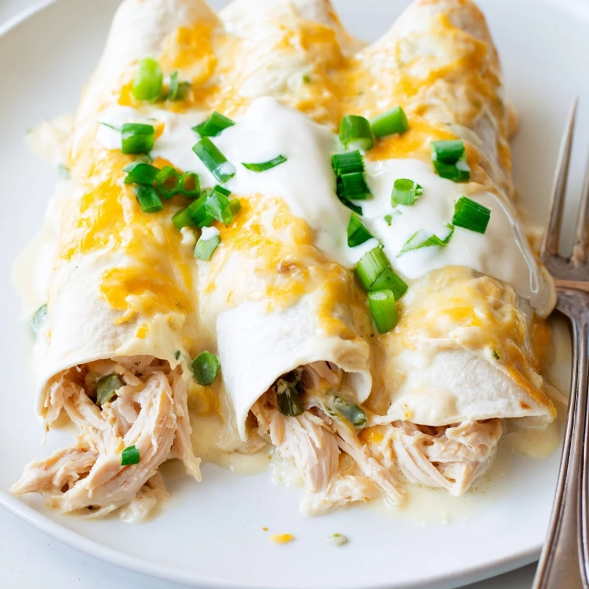 Serve White Rotisserie Chicken Enchiladas hot with cilantro, rice, and tangy sour cream