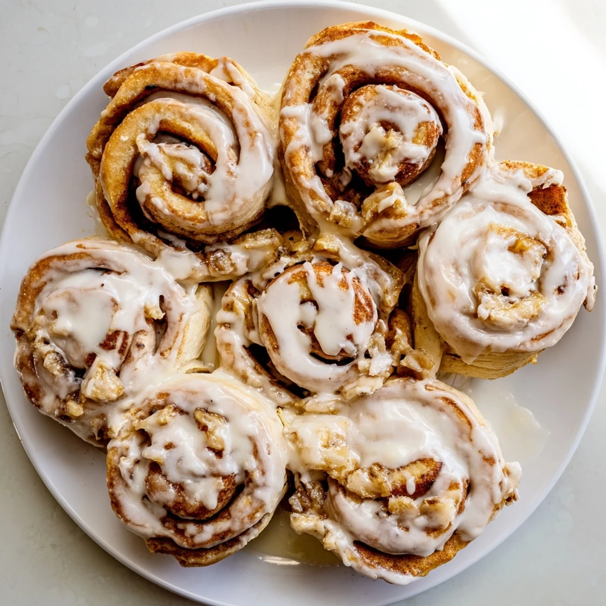 Golden banana cinnamon rolls spiraled with sweet banana slices and topped with cream cheese frosting