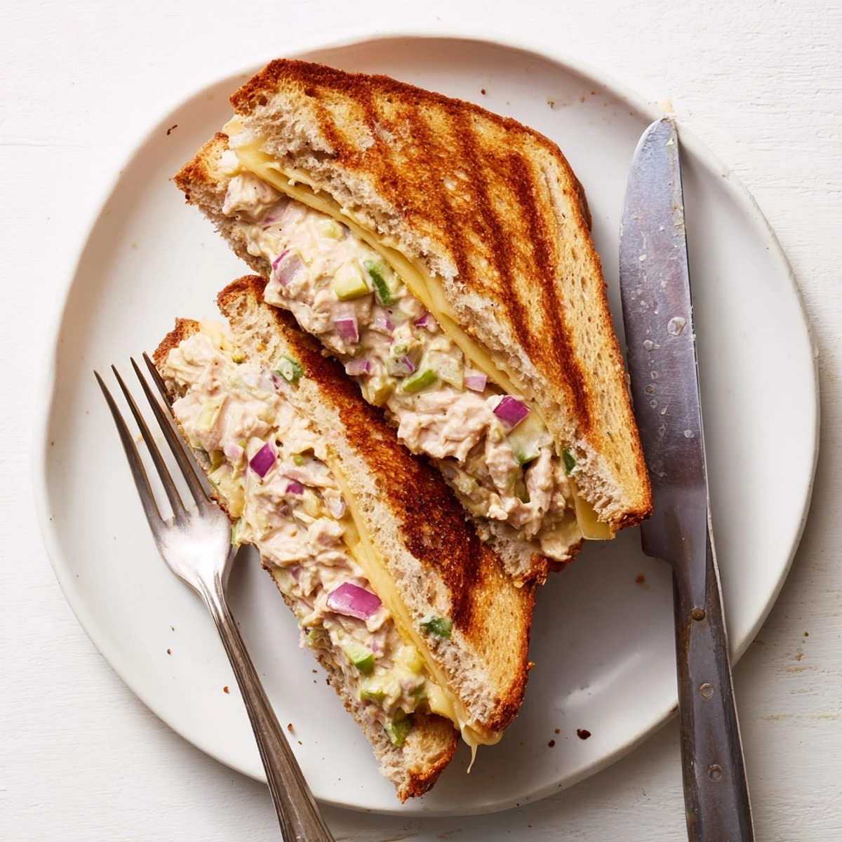 Golden brown Tuna Melt sandwich oozing melted Swiss cheese with crispy grilled bread