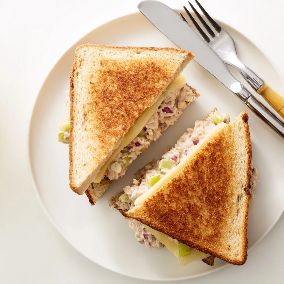 Classic American Tuna Melt sandwich cut in half revealing steaming melted cheese inside