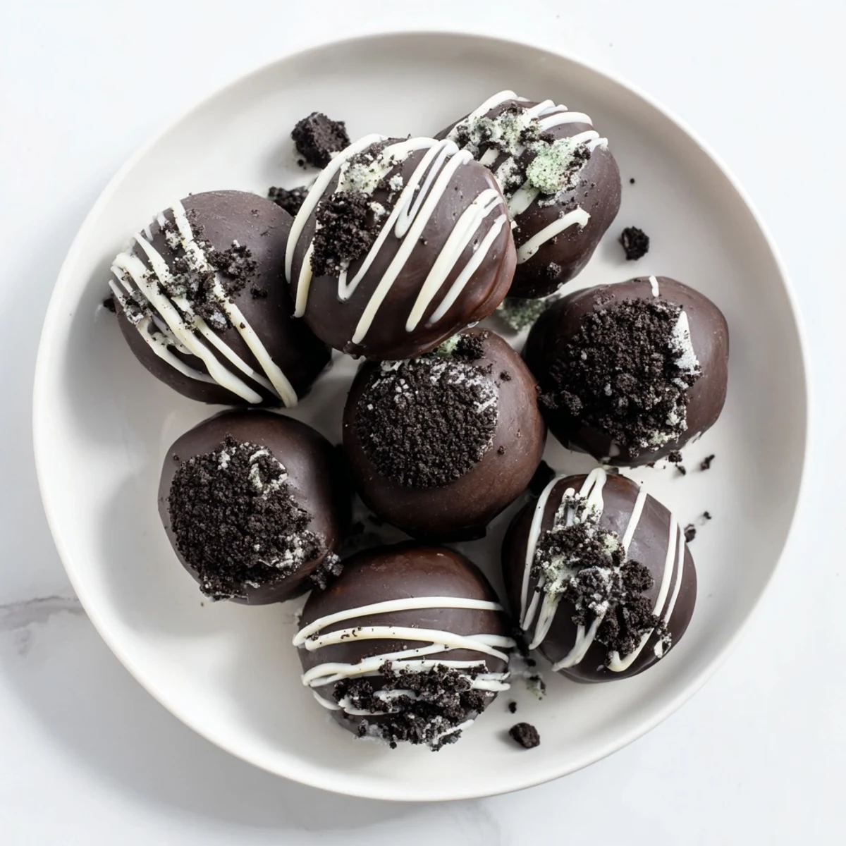 Rich homemade mint Oreo truffles drizzled with white chocolate on a serving platter