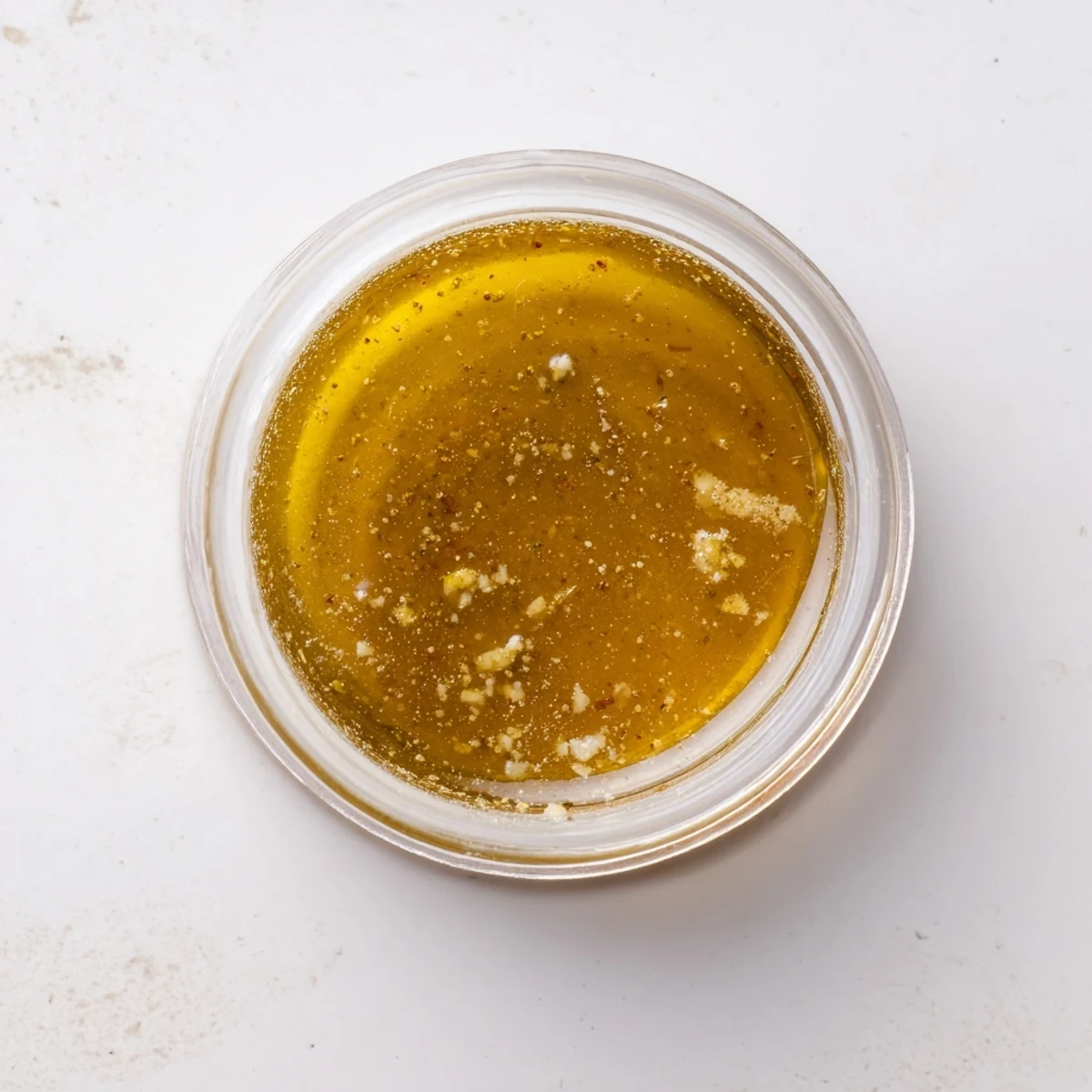 Golden honey mustard vinaigrette drizzled over fresh green salad in glass bowl