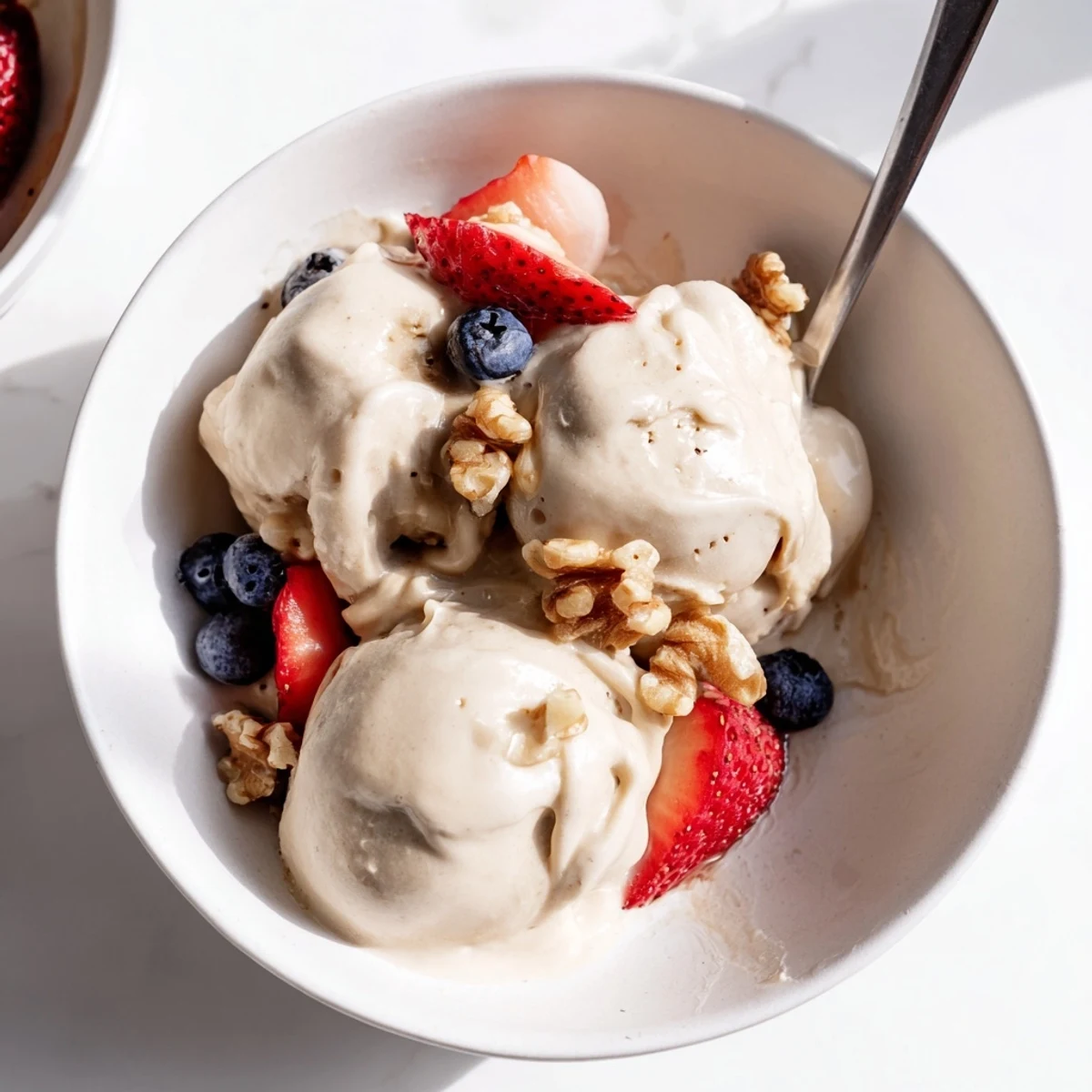Vegan banana nice cream recipe scooped into a white bowl with chocolate chip garnish