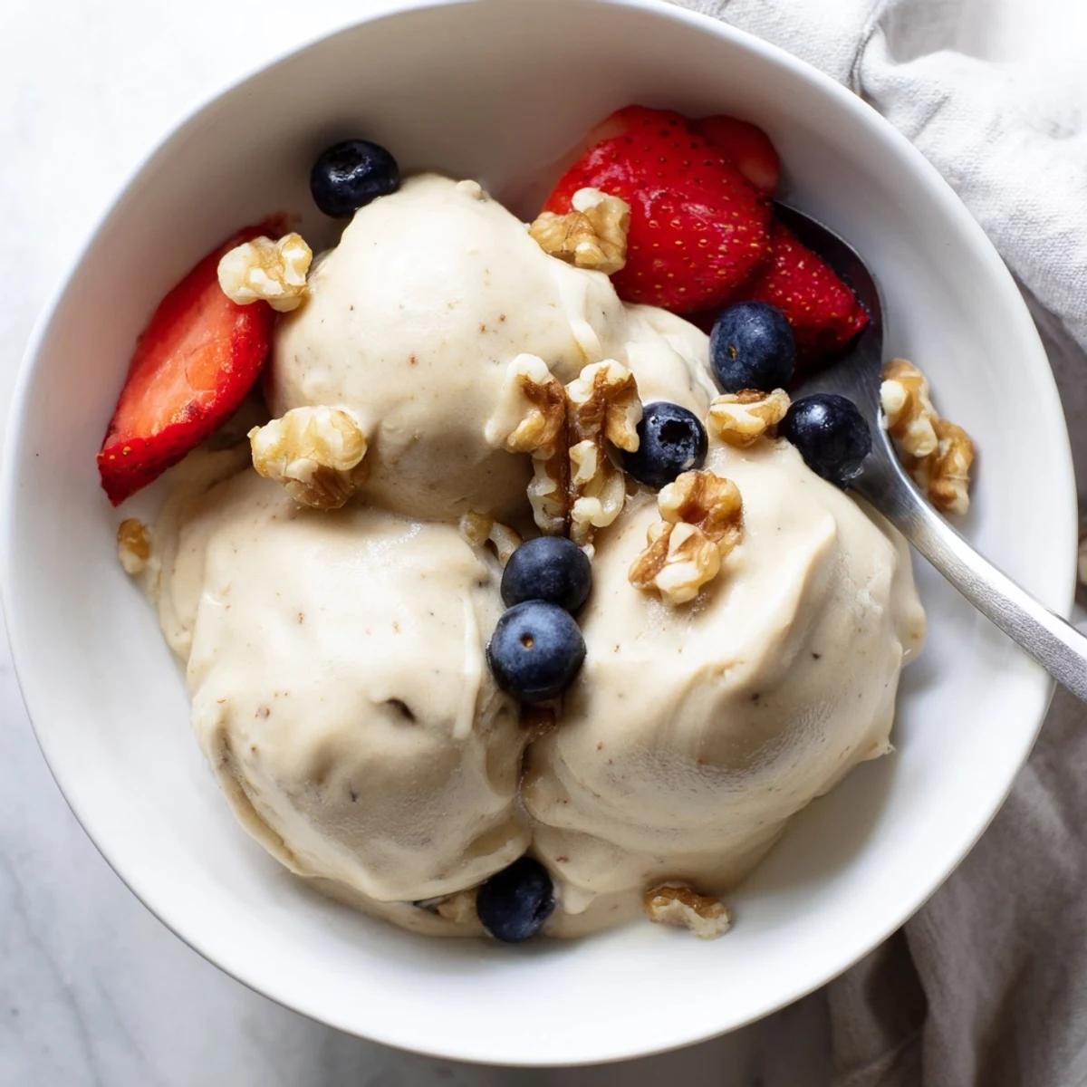 Dairy-free banana nice cream with smooth soft serve texture swirl in a glass dish