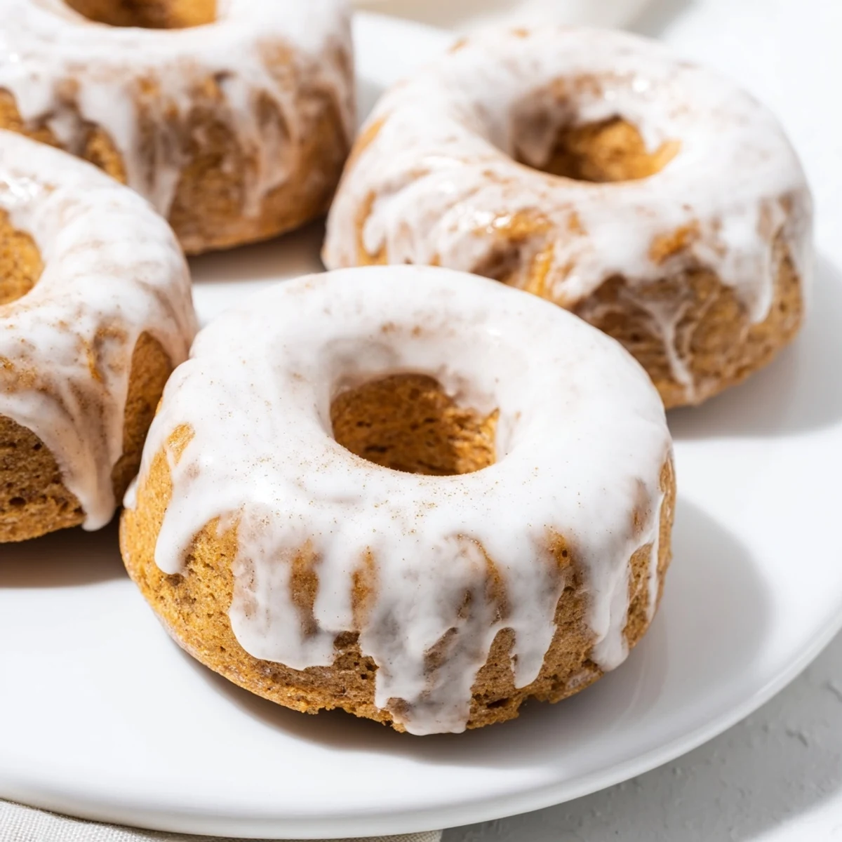 Soft moist banana bread donuts topped with cinnamon sugar on white plate