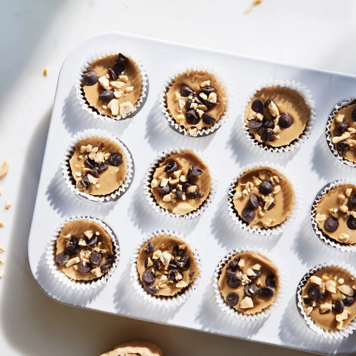 Frozen peanut butter Greek yogurt bites arranged in a muffin tin with chocolate chip toppings