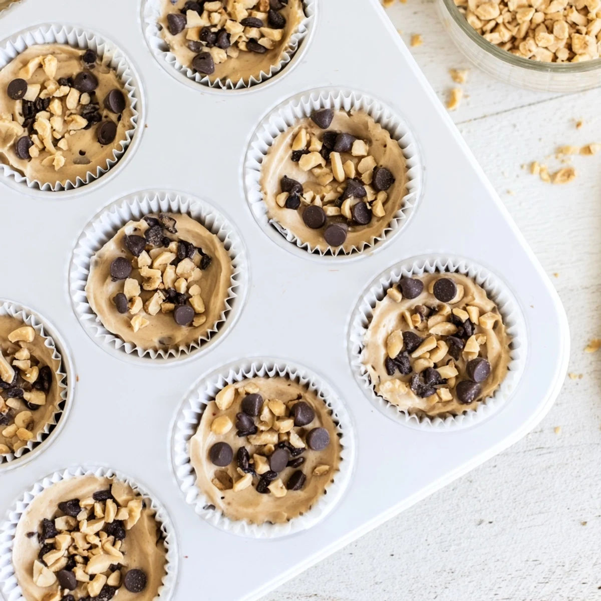 White mini muffin liners filled with frozen peanut butter Greek yogurt bites ready for freezing