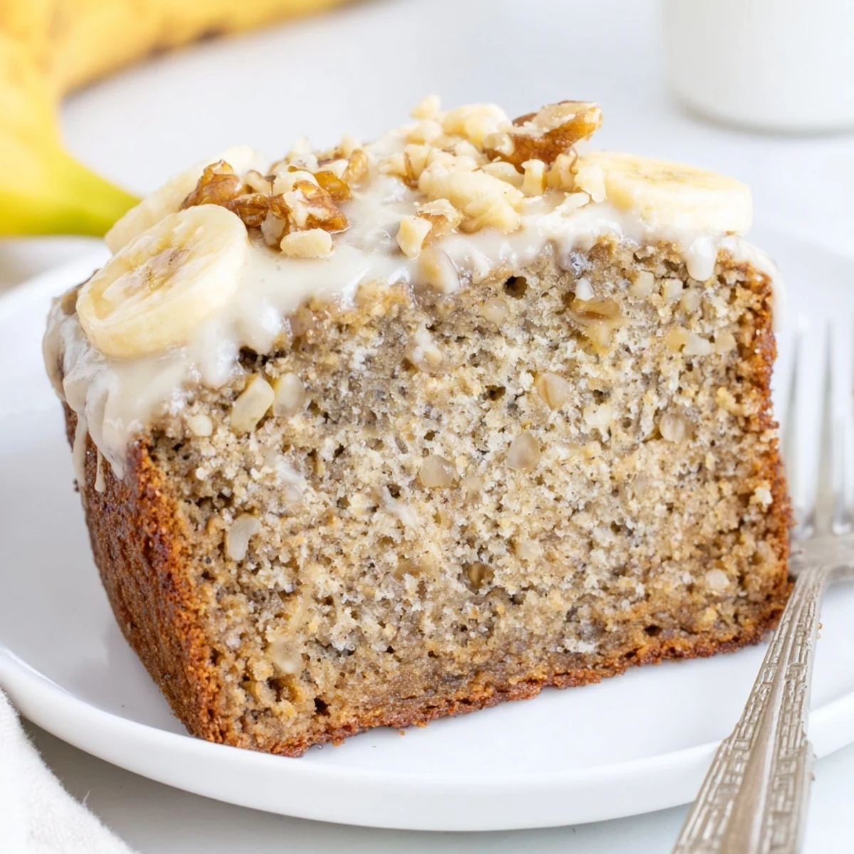 Slice of moist banana cake with golden crumb, served with coffee
