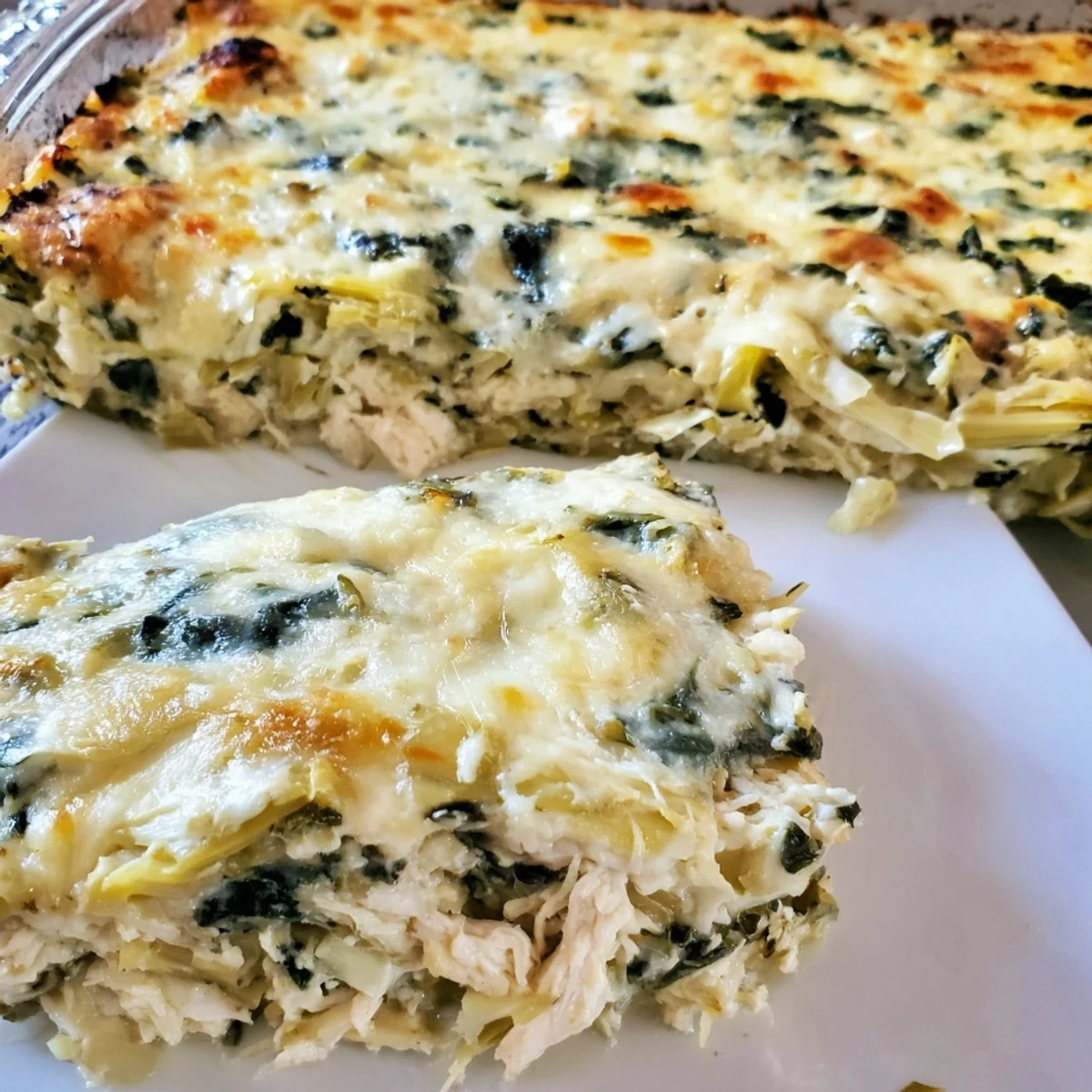 Homemade spinach artichoke chicken casserole featuring tender chunks and golden brown mozzarella crust