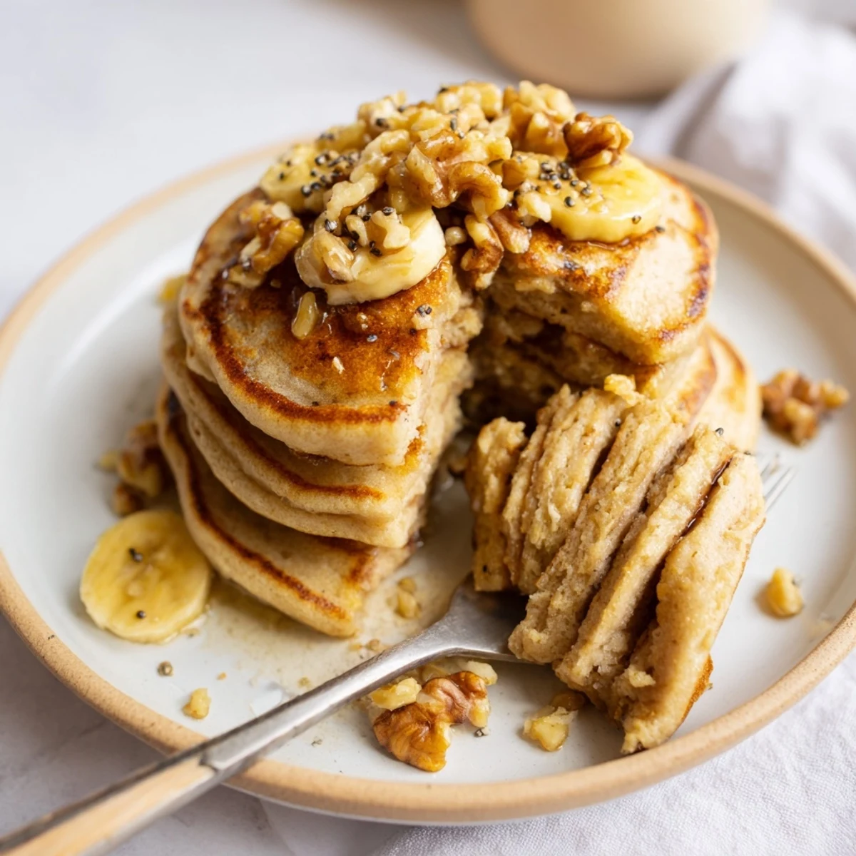 Golden stack of protein banana pancakes topped with fresh berries and maple syrup