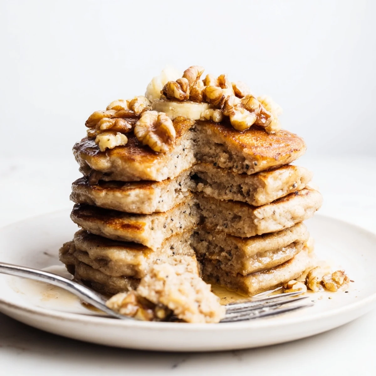 Fluffy protein banana pancakes cooking in a skillet with bubble textures forming