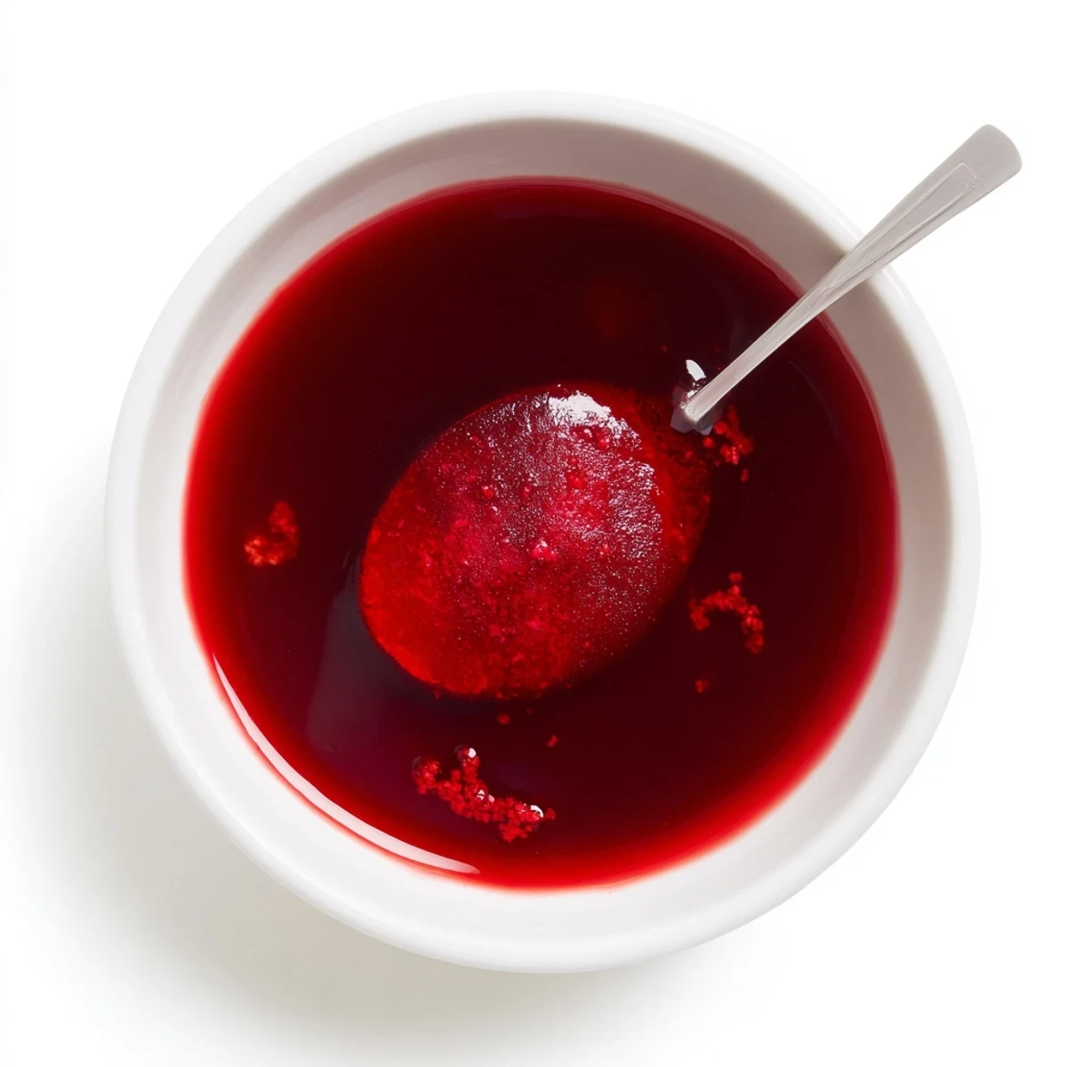 Homemade cranberry syrup simmering in saucepan with burst berries releasing vibrant ruby juices