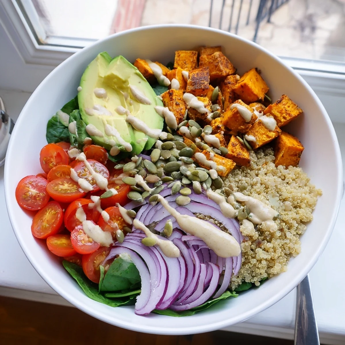 Hearty Sweet Potato Bowl layered with quinoa, roasted vegetables, and a zesty sesame sauce