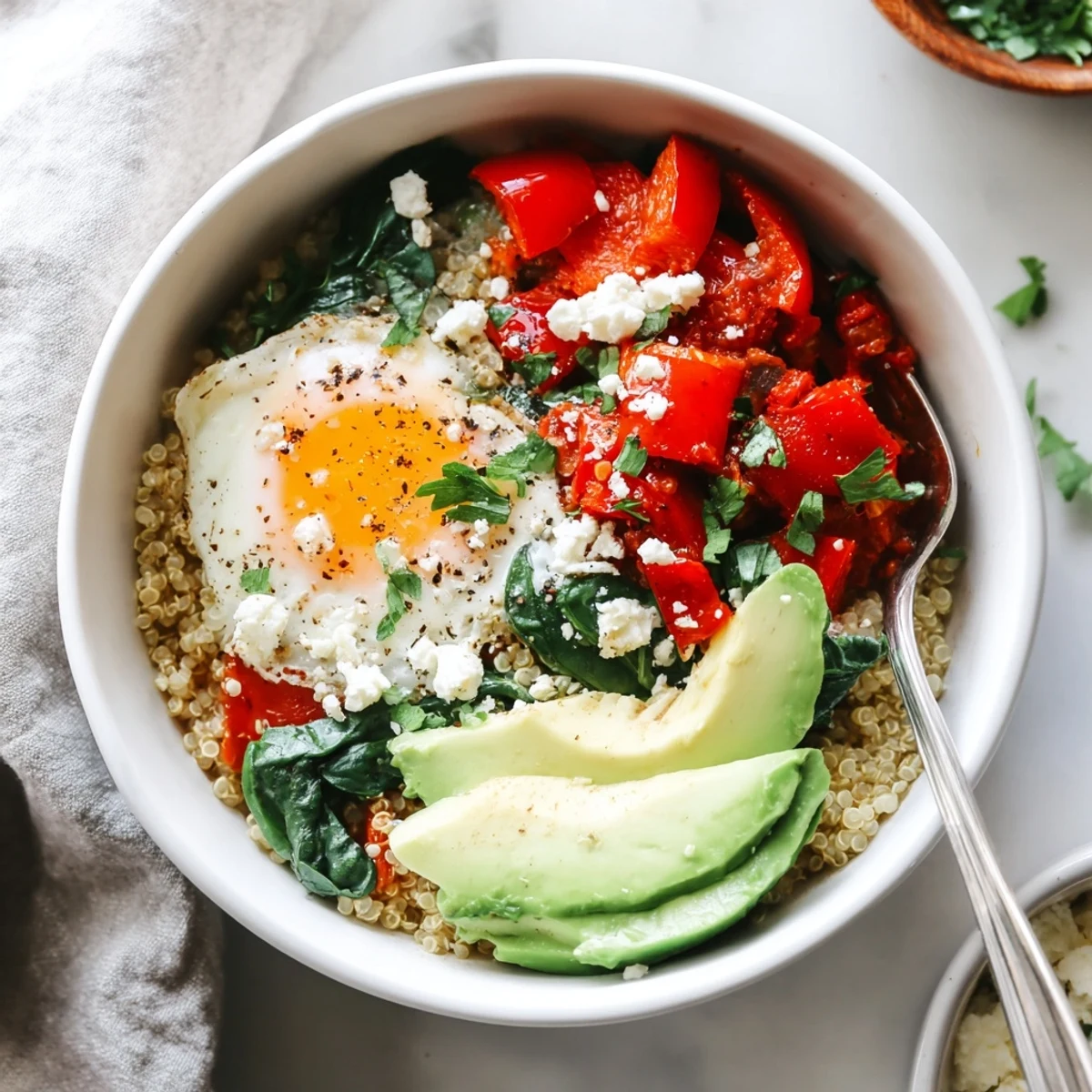 Golden savory quinoa breakfast bowl topped with a runny egg and fresh vegetables