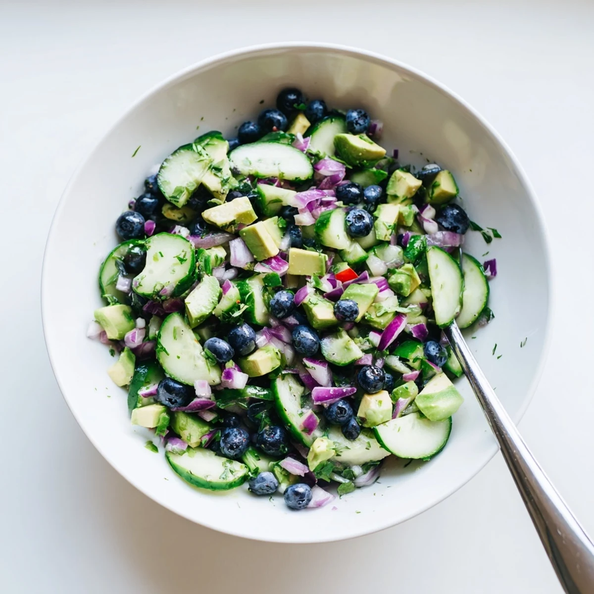 A bowl of blueberry cucumber salsa with bright lime juice, fresh cilantro, and red onion