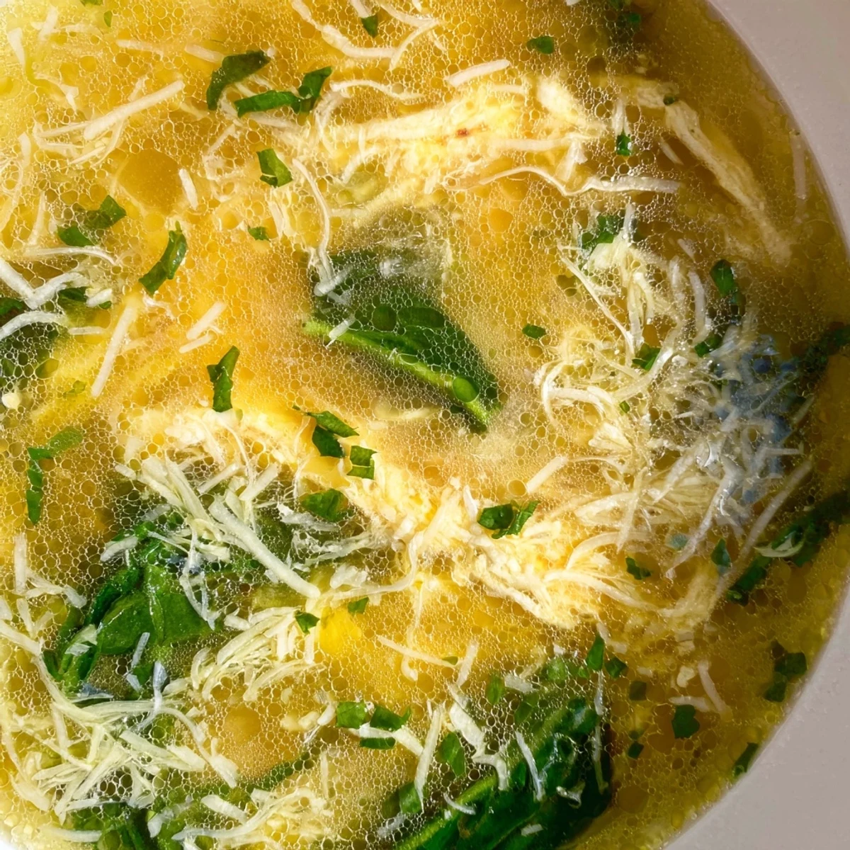 Steaming bowl of Stracciatella Soup with delicate egg ribbons and fresh spinach