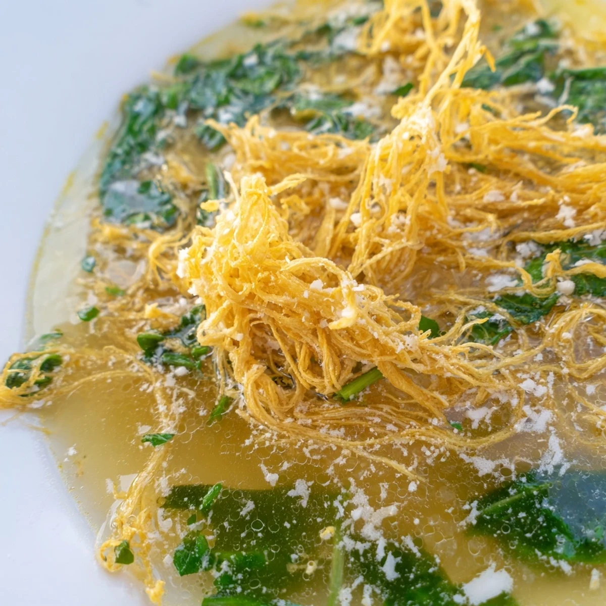 Golden egg curds floating in a rich Parmesan Stracciatella Soup broth