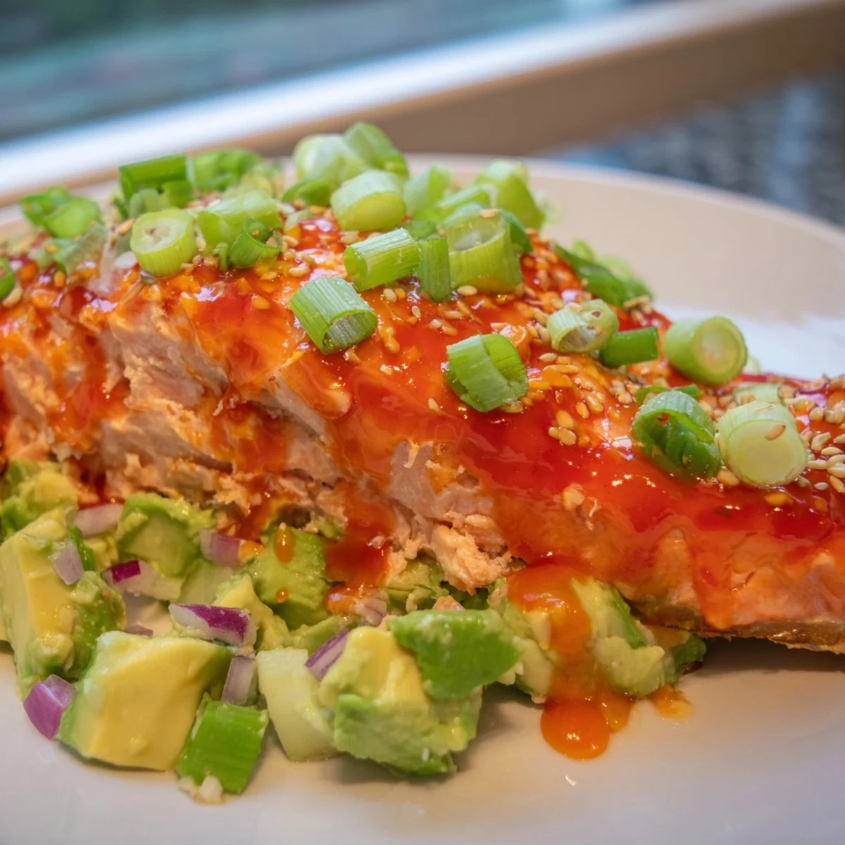 Pan-seared Bang Bang Salmon drizzled with spicy cream sauce over fresh avocado cucumber salsa