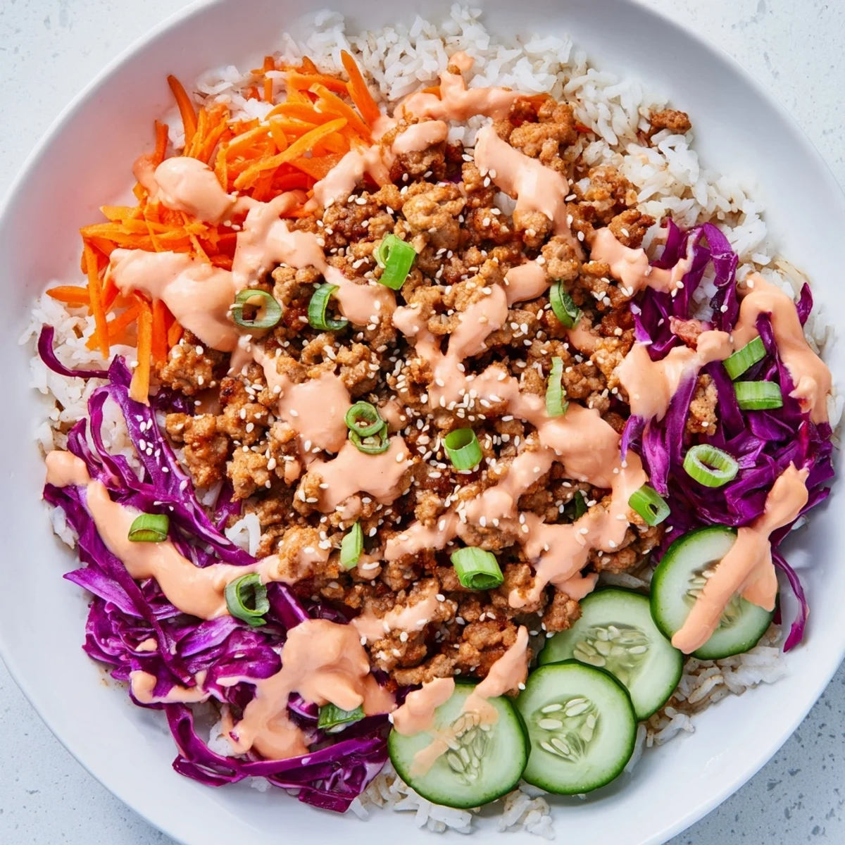 Ground Turkey Rice Bowls drizzled with creamy, spicy Bang Bang sauce over fresh vegetables