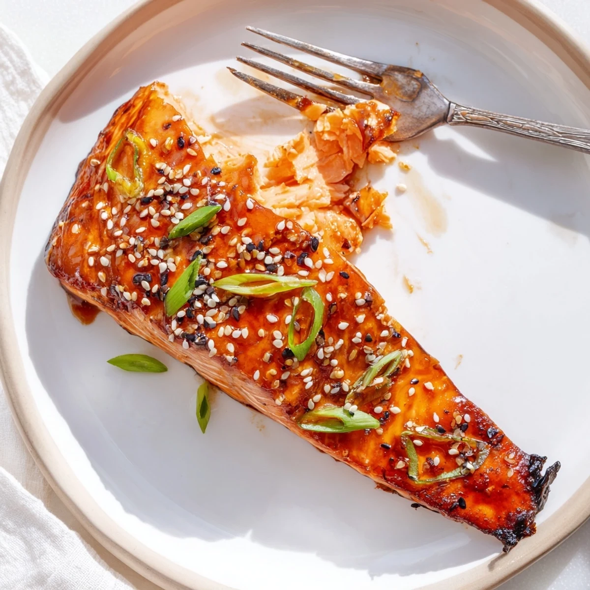 Glistening baked Asian salmon fillet drizzled with sticky soy glaze and sprinkled sesame seeds on a parchment-lined baking sheet