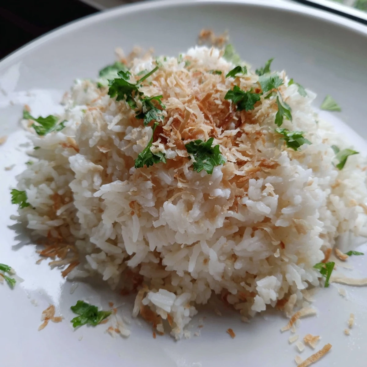 Steaming bowl of fluffy coconut rice served alongside a rich Thai curry