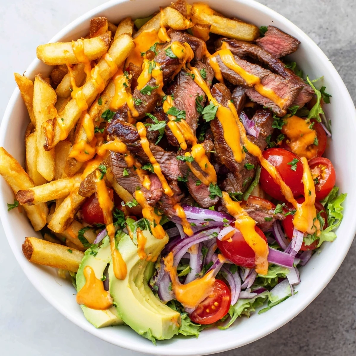 Tender seared steak strips crispy fries bowl drizzled with creamy zesty sauce