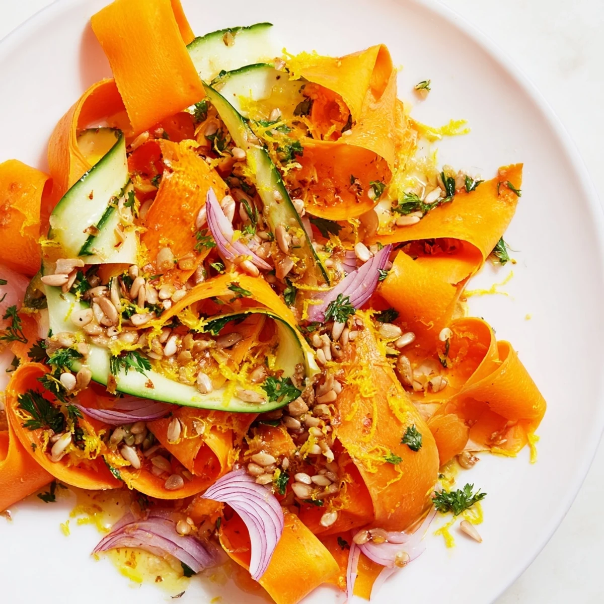 Thinly shaved carrot ribbons drizzled with tangy honey lemon dressing on a platter.  