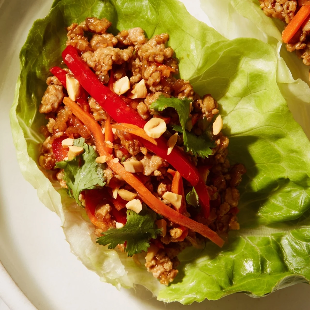 Savory Thai chicken lettuce wraps topped with peanuts and fresh herbs for a crisp bite.