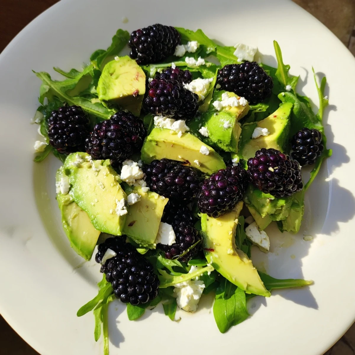 Vibrant bowl of blackberry avocado salad topped with feta cheese and toasted pecans  