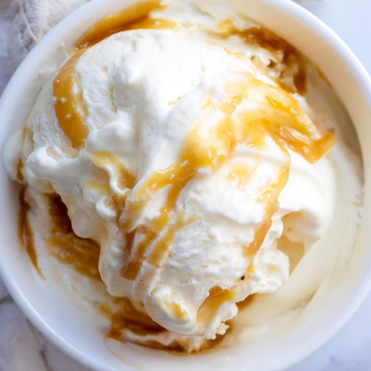 Scoop of rich salted caramel ice cream melting in a chilled bowl.  