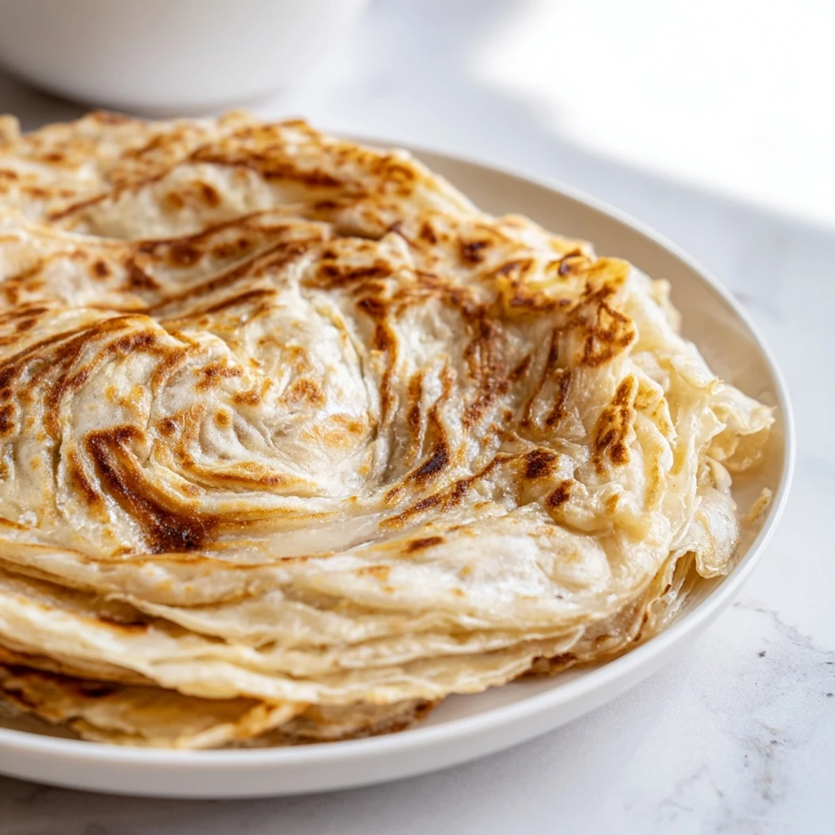 Delicious Roti Canai flatbread boasts airy layers and a warm, buttery texture.